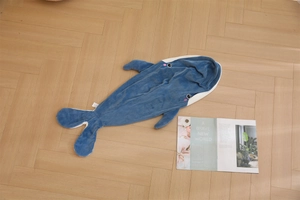 Detailopname van blauwe walvis pluche kussenhoes met borduursel op houten vloerbedekking