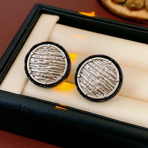 Detail of round silver earrings with black enamel and rippled texture in a gift box