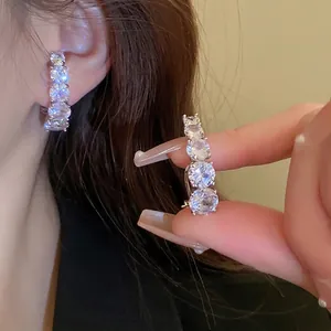 Elegant curved silver earrings with four graduated cubic zirconia stones on model