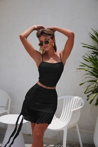 Detail view of black ruffled camisole and side-tie mini skirt with elastic texture