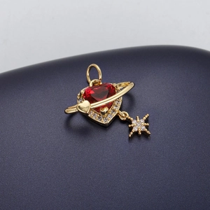 Macro detail of 18K gold-plated celestial pendant with red heart stone and star charms