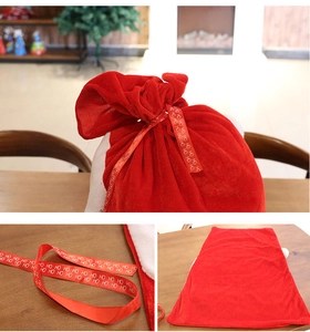 Detail of red velvet Christmas gift bag with festive HO HO HO printed ribbon ties