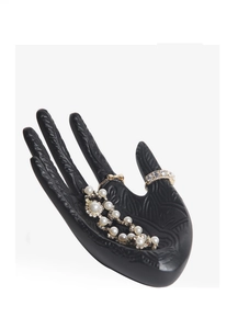Detail of matte black hand-shaped jewelry stand showing ring display with relief texture