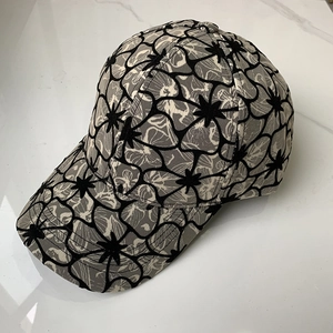 Stylish floral baseball cap with abstract black and grey patterns on a marble surface