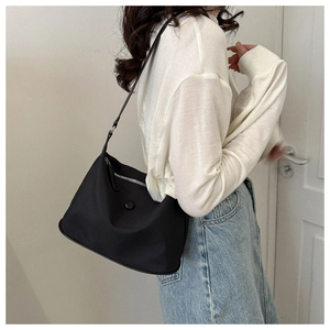 Vue latérale d'un sac bandoulière noir en tissu oxford avec détails argentés sur mannequin