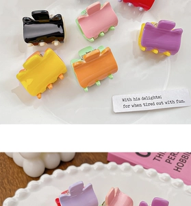 Close-up of assorted candy-colored mini hair claws on a decorative ceramic plate