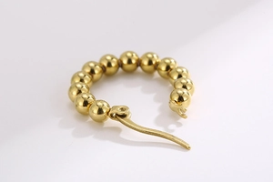 Close-up of golden beaded hoop earrings in polished titanium steel with secure buckle clasp