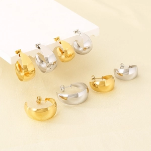 Macro view of wide C-shaped stainless steel earrings in gold and silver glossy finish