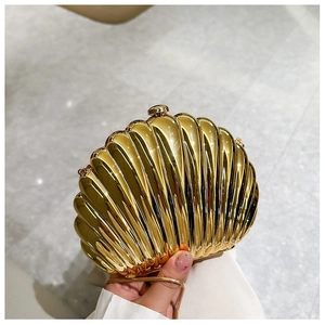 Close-up of golden shell evening bag featuring a radiant pleated texture and metal clasp