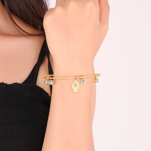 18K gold plated evil eye and Hamsa hand open bangle on a female wrist detail view