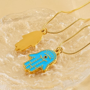 Golden Hamsa Hand necklace with blue evil eye pendant on a stylish glass tray