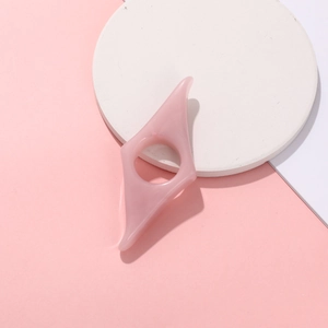 Macro view of a pink resin thumb book page holder with unique geometric hole design