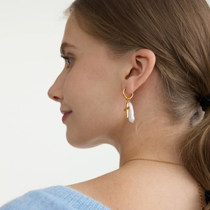 Close-up of 18K gold plated hoop earrings with baroque pearl and cross pendant on model