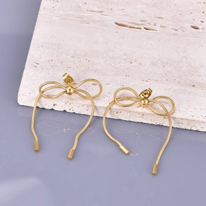 Minimalist 18K gold bow snake chain earrings displayed on a textured stone block