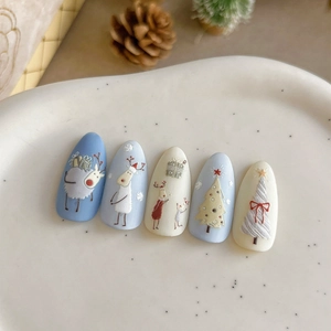 Christmas themed 3D press-on nails with blue reindeer and white tree patterns on ceramic tray