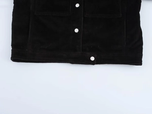 Détail du tissu en velours côtelé noir avec boutons-pression en métal blanc veste