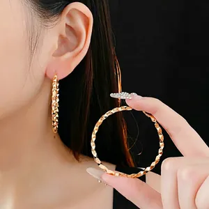 Elegant large golden hoop earrings with diamond-cut texture on minimalist silver needle