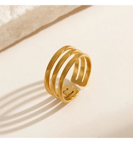 Detail of adjustable triple-layer gold stainless steel ring on beige rock surface