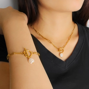 Dettaglio del set collana e bracciale dorato in acciaio con perla e chiusura a levetta OT