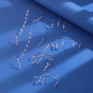 Dettaglio di cinque bracciali da dito in oro e zircone su sfondo blu scuro profondo
