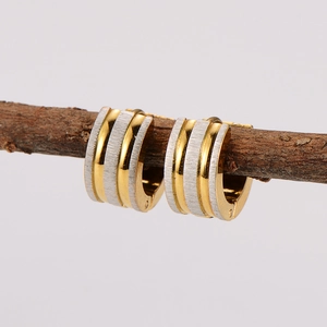 Three-layer two-tone gold and silver striped huggie hoop earrings hanging on a branch