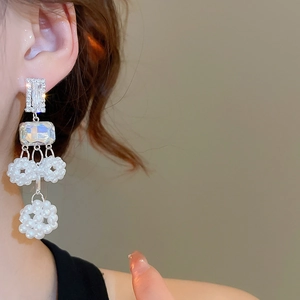 Close-up of elegant silver drop earrings with baguette crystals and white beaded tassels