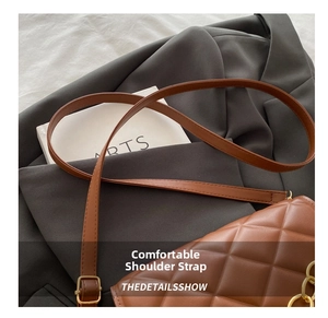 Detailed view of brown quilted crossbody bag with adjustable strap and chain link details