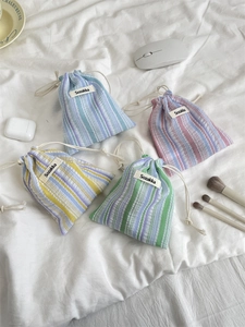 Set of four striped drawstring storage bags in blue, pink, yellow, and green cotton linen