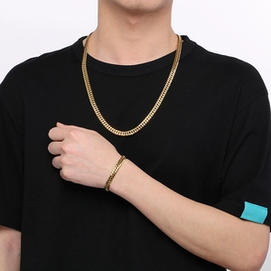 Gros plan d'un ensemble collier et bracelet pour hommes en maille gourmette dorée de 7mm