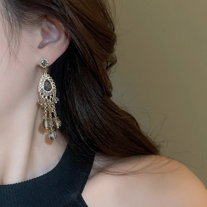 Close-up of bohemian tassel earrings with smokey grey crystals on a model