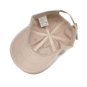 Dettaglio della trama in cotone e dell'etichetta di lavaggio di un cappello beige