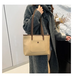 Dettaglio borsa shopper beige con tasca frontale e manici marroni a contrasto
