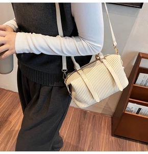Detail der cremefarbenen Boston-Tasche mit vertikaler Faltenstruktur und Goldmetall