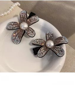 Close-up of floral hair clips with sparkling rhinestones and center pearls in a tray