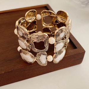 Detailed macro view of vintage gold elastic bracelet with white marble resin inserts