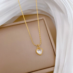 Close-up of a gold heart pendant with crystal inlay on a delicate chain over silk