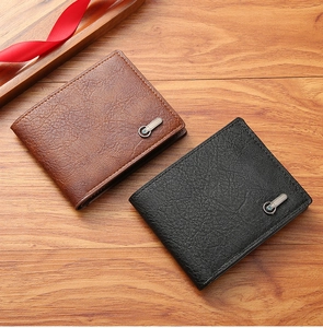 Portefeuilles homme en cuir marron et noir avec ruban rouge sur fond en bois naturel