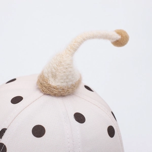 Detailaufnahme des beigen Baby-Sonnenhuts mit Punkten und gestrickter Antenne mit Bommel
