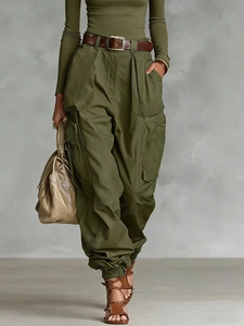High-waist olive cargo pants with brown leather belt and beige handbag in street style