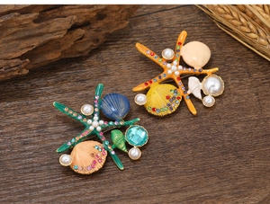 Detailed macro of enamel starfish and shell brooches with pearls on a wooden surface