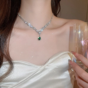 Close-up of model wearing luxury V-shaped silver necklace with green teardrop zircon pendant