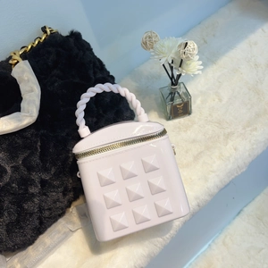 Lavender mini jelly bucket bag with pyramid studs and twisted handle in a stylish setting