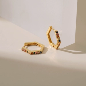 18K gold plated hexagonal earrings with rainbow cubic zirconia set on a white minimalist block