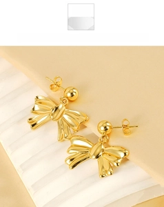 Detailed view of elegant 18k gold plated stainless steel bow earrings on silk fabric