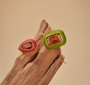 Macro shot of gold S925 silver ring with red and green enamel and amber zircons on wood