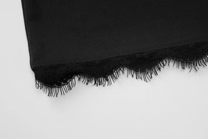 Makroaufnahme von feiner Wimpernspitze am Saum eines schwarzen Sommerkleids aus Strick