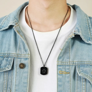 Men's black stainless steel urn necklace featuring a dog paw print pendant on a model