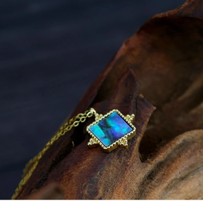 Macro detail of French vintage square abalone shell pendant on natural wood background