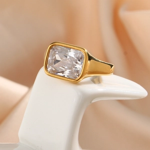 Macro shot of gold stainless steel ring with square white zircon on a silk background