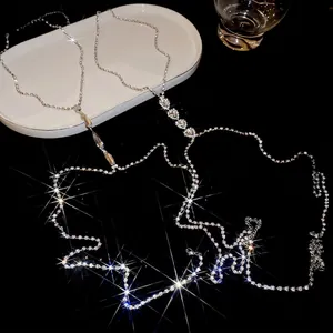 Luxury rhinestone body chain with heart and waterdrop pendants over a ceramic tray